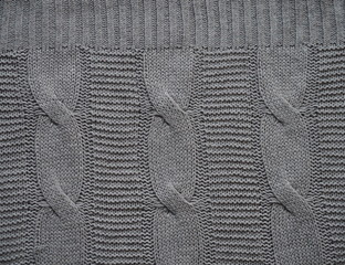 Knitted fabric texture. Gray. Simple knitting with front and back loops. Knitting on the knitting needles. Horizontal lines.
