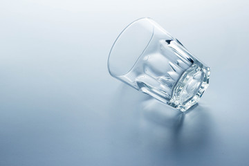 Clear water glass placed lay down on a bright background.