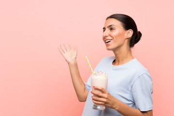 Young woman with strawberry milkshake over isolated pink background with surprise facial expression