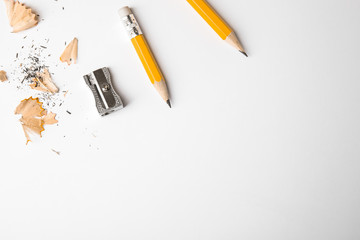 Graphite pencils, shavings and sharpener on white background, top view. Space for text