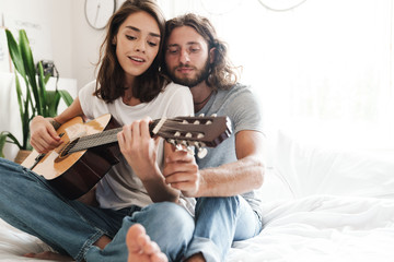Loving couple indoors at home play on guitar.