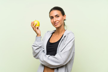 Young sport woman with an apple over isolated green background