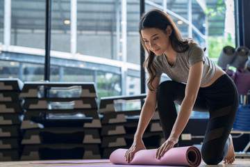 Fototapeta na wymiar Asian woman rolls her mat after studying yoga at fitness club.