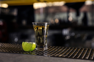 Mexican Tequila shot with lime slice on bar counter. Space for text