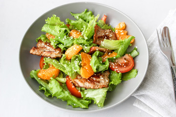 Salad with sweet tangerines and pieces of pork