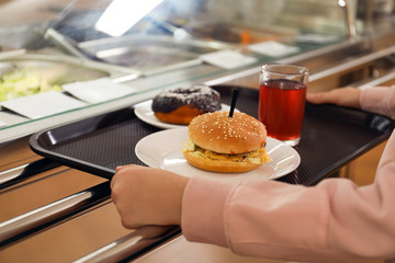 Little girl with plastic tray near serving line in canteen, closeup. School food