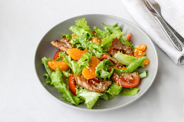 Salad with sweet tangerines and pieces of pork