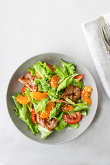 Salad with sweet tangerines and pieces of pork