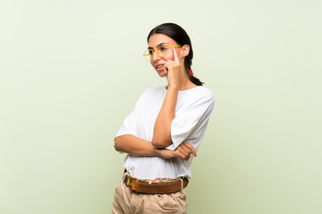 Young woman over isolated green background with glasses