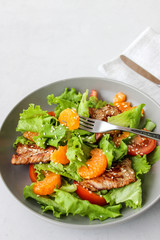 Salad with sweet tangerines and pieces of pork