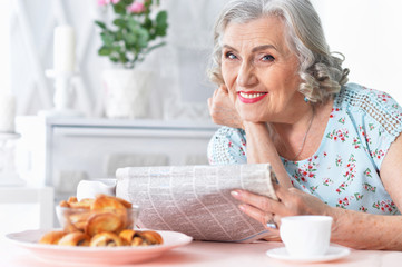 Portrait of thoughtful aged woman reading newspaper