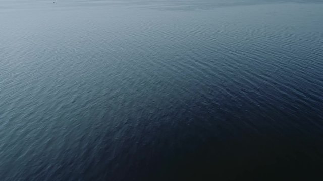 Aerial video of endless, blue, empty sea or ocean water surface at sunset. 