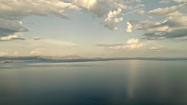 Scenic, picturesque aerial video of Mediterranean sea in the summer with beautiful clouds reflecting in the water and mountains on the horizon. 