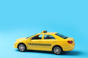 Yellow taxi car model on light blue background. Space for text