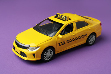 Yellow taxi car model on purple background