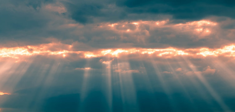 A background from a heavy dark thunderstorm sky with oblique rays of sun breaking through the clouds. State of the atmosphere before the storm © Naletova