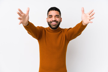 Young latin man against a white background isolated feels confident giving a hug to the camera.