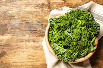 Fresh kale leaves on wooden table, top view. Space for text