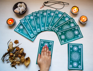 Fortune teller girl with blue tarot cards on a white wooden tabl