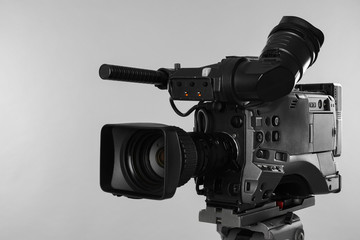 Modern professional video camera on light background