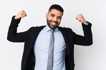 Young latin business woman against a white background isolated showing strength gesture with arms, symbol of feminine power