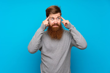 Redhead man with long beard over isolated blue background having doubts and thinking