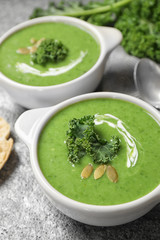 Tasty kale soup with pumpkin seeds on grey table
