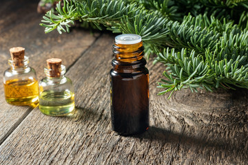 Bottles of essential oil with fresh fir branches