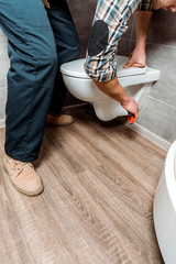 cropped view of man installing white toilet