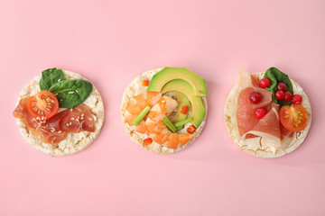 Puffed rice cakes with different toppings on pink background, flat lay