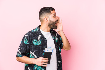 Young arabian cool man holding a boarding passes isolated shouting and holding palm near opened...