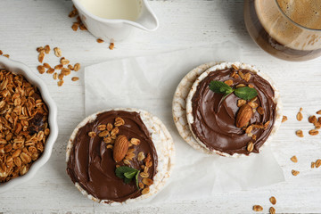 Puffed rice cakes with chocolate spread on white wooden table, flat lay