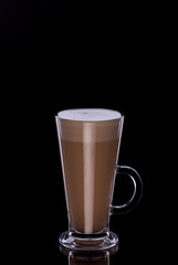 Latte coffee in glass cup with foam on black background