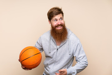 Redhead man with long beard over isolated background with ball of basketball