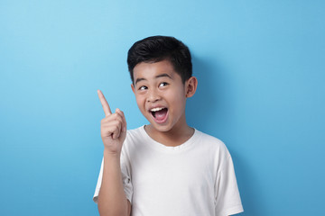 Happy Asian boy pointing finger up, having idea gesture