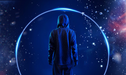 Obraz premium Back view of hacker in hoodie. Dangerous hooded hacker. Internet, cyber crime, cyber attack, system breaking and malware concept. Anonymous. Dark background. Blue neon light.