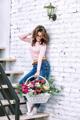 Young adult beautiful and happy woman model with flowers in her hands portrait on a bright staircase