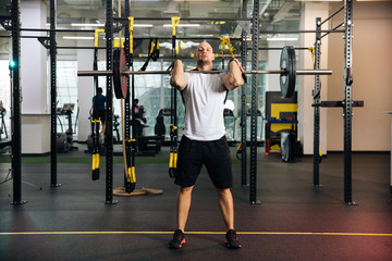 The young sports guy is engaged in fitness, lifestyle, sports and healthy eating, in the gym a man is doing exercises,bench press and barbell lift