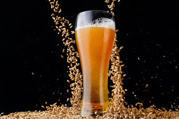 glass of beer with foam on black background