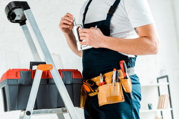 cropped view of installer with tool belt holding construction stapler