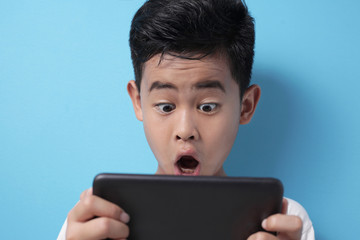 Asian boy shocked when looking at his tablet