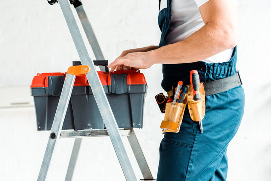 cropped view of installer standing on ladder and holding tool box
