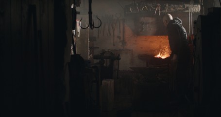 Blacksmith heating a piece of iron for forging in his workshop