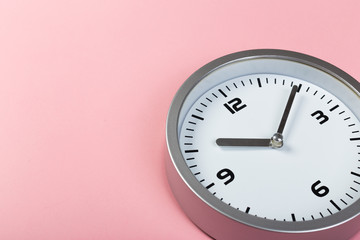 White wall clock with a yellow used hanging on the wall. Minimalist image of a wall clock on a pink background with copy space