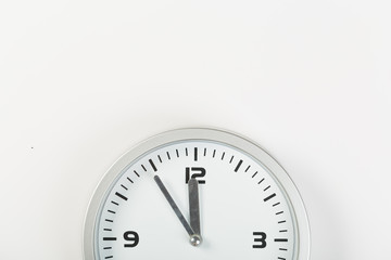 Obraz na płótnie Canvas White wall clock with a yellow used hanging on the wall. Minimalist image of a wall clock on a light gray background with copy space
