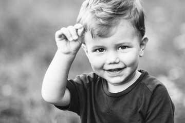 Black and white photo of cute little blond boy smiling. Happy children