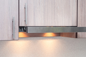 Mounting hoods in a kitchen interior with wooden elements. Minimalism in the interior. Plastic Button to turn on the backlight in the kitchen hood.