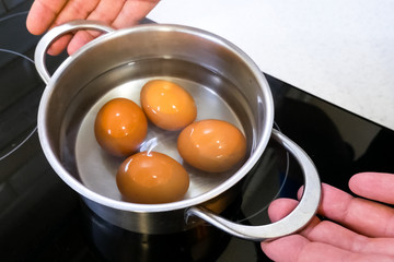 Boiled eggs in pan are removed from the stove.