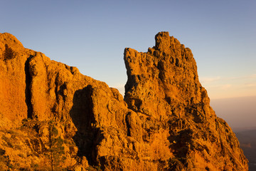 Climbers with ropes on brown rock mountain at sunset in Pico de las Nieves, Canary Islands. People climbing on highest peak at golden hour in Gran Canaria, Spain