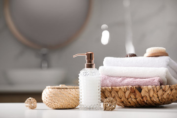 Soap dispenser, towels and brush on white table indoors